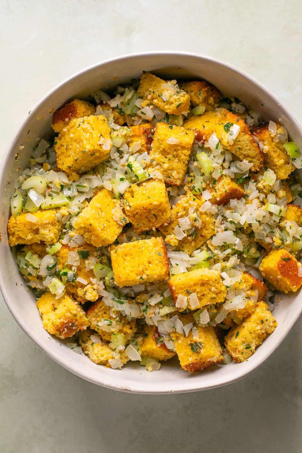 cubed gf cornbread and cooked onion and celery in a mixing bowl.