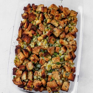 gluten free stuffing in a glass casserole dish topped with fresh herbs