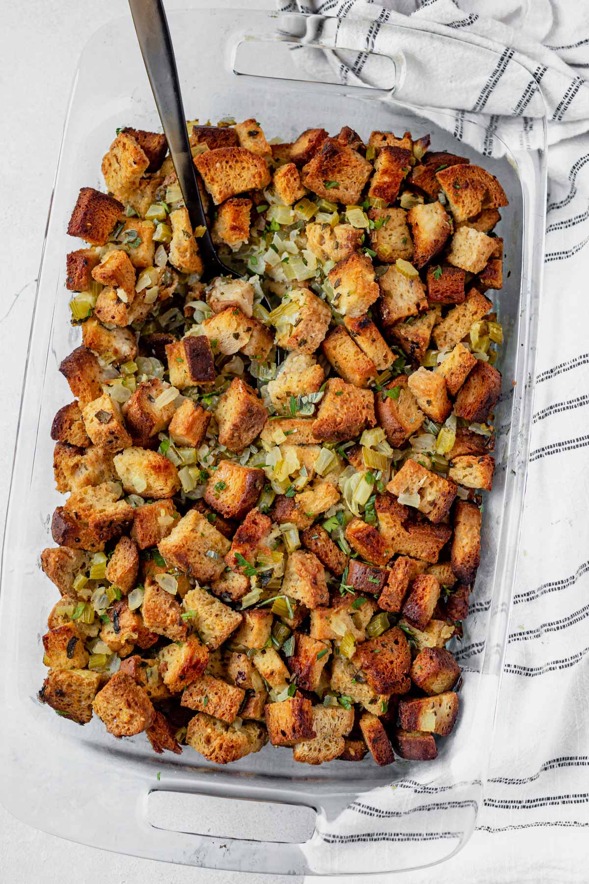 gluten free stuffing in a 9x13 glass dish with a serving spoon