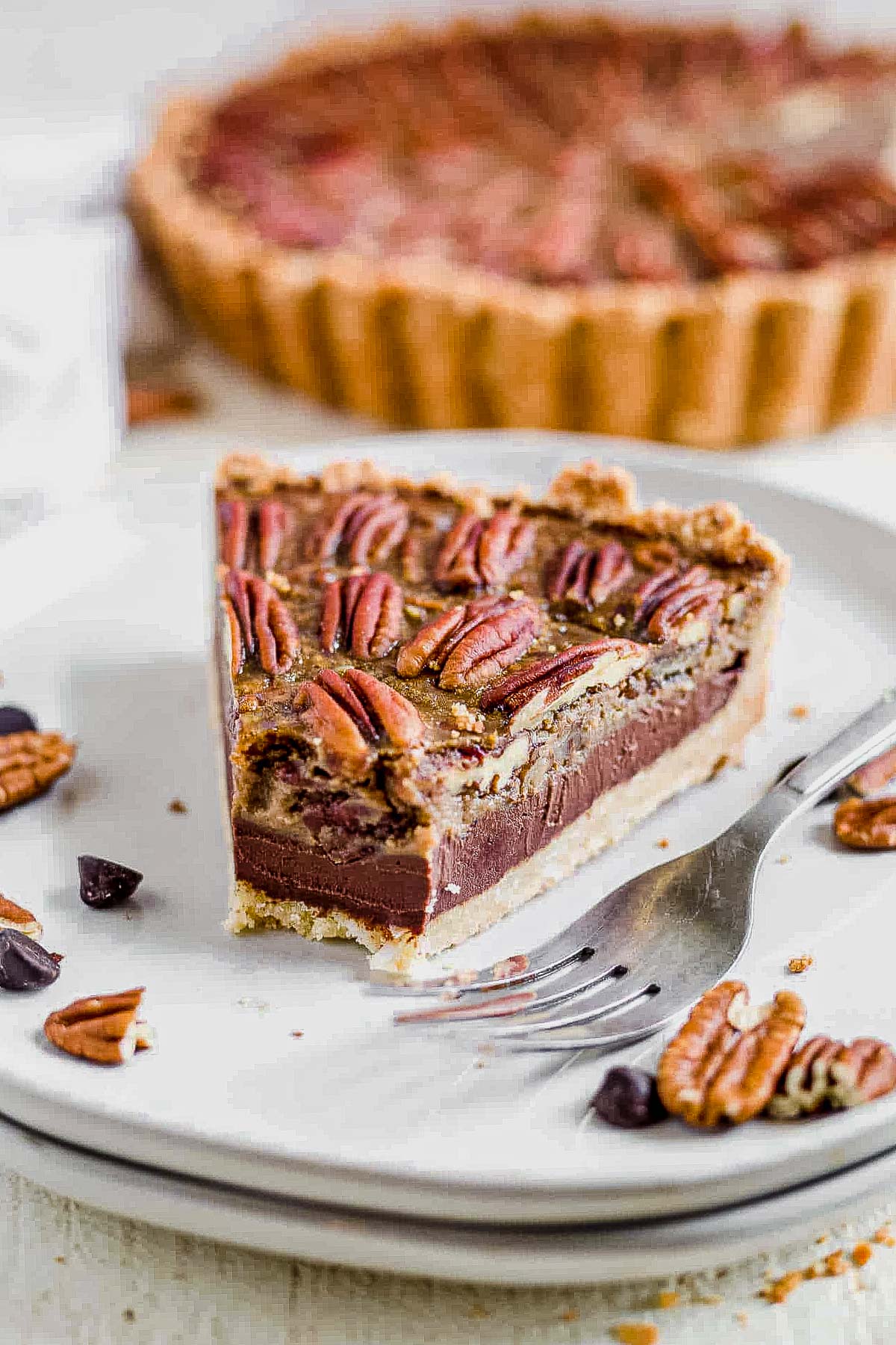 chocolate paleo pecan pie on a white plate with a bite taken out