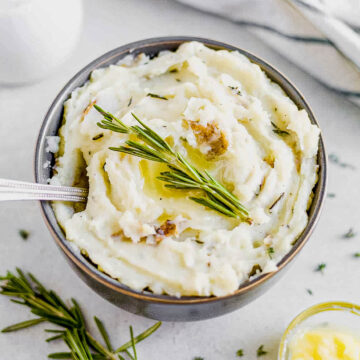 dairy free mashed potatoes in a serving bowl with fresh herbs