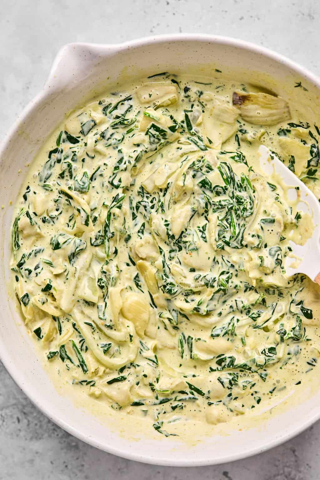 creamy spinach mixture combined in a mixing bowl.