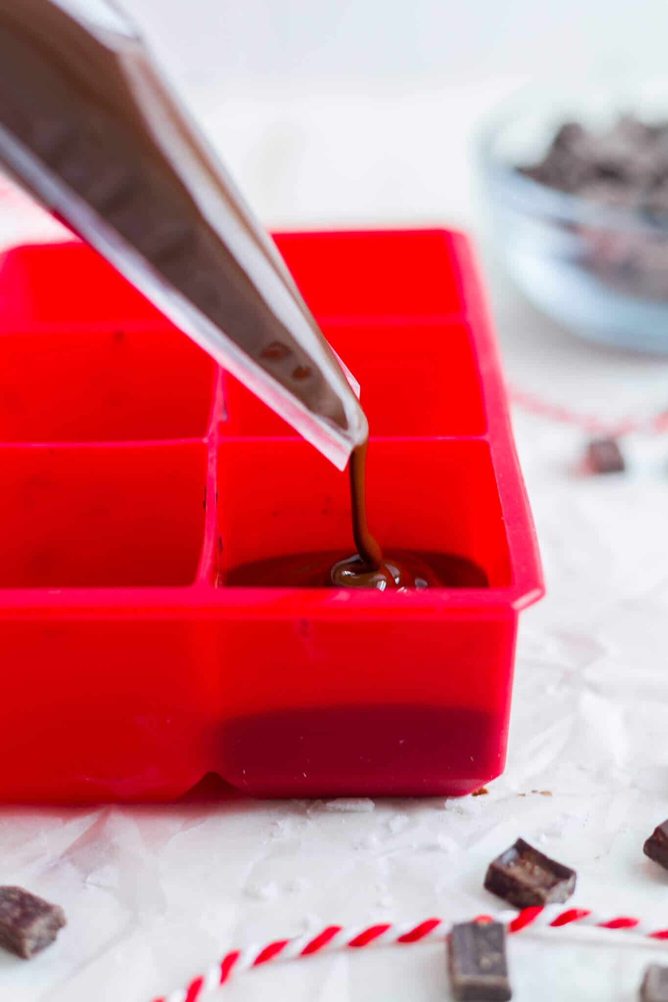 filling ice cube trays with hot chocolate for hot chocolate on a stick