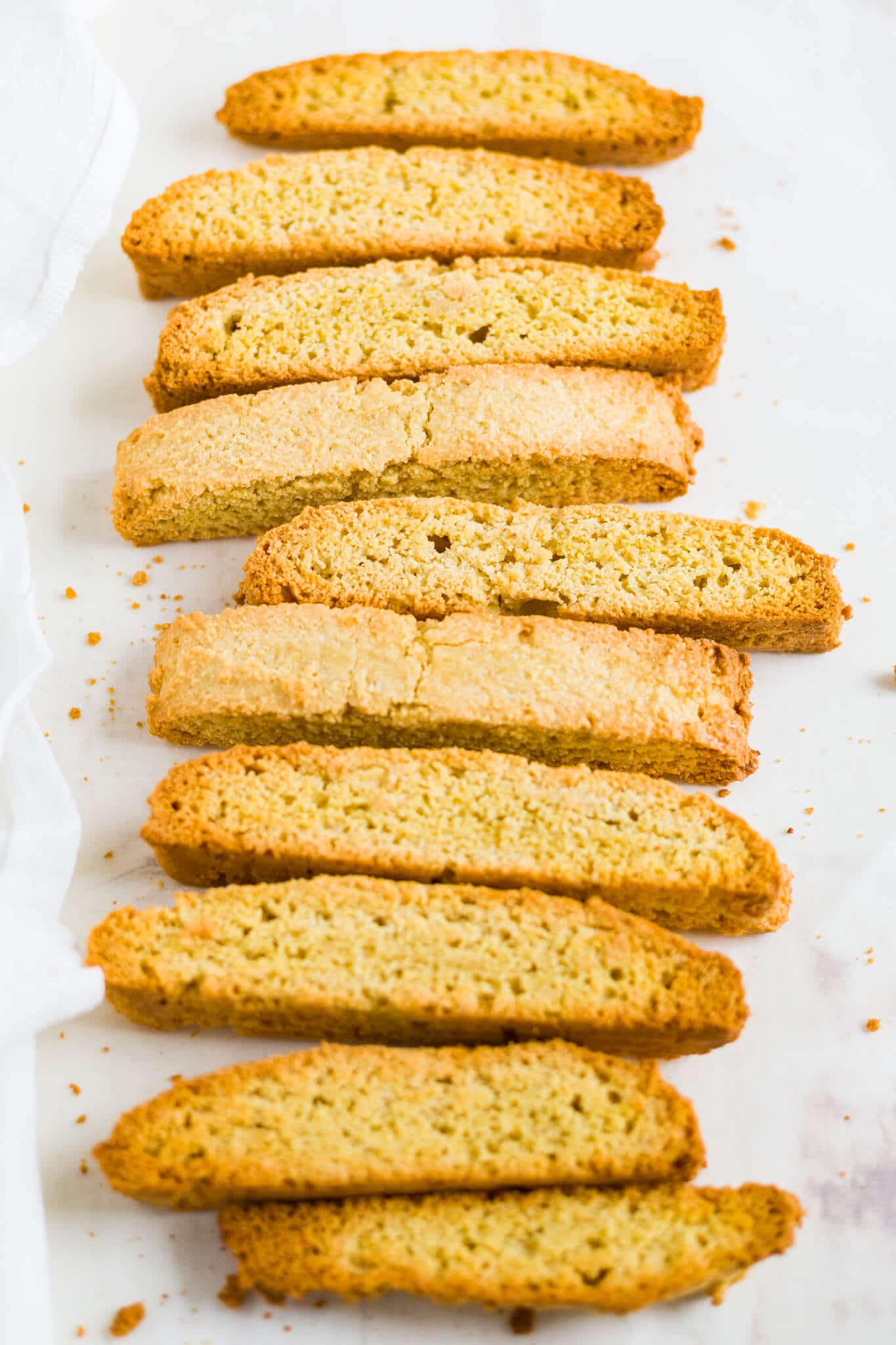 crunchy golden brown almond flour biscotti in a row on a piece of parchment paper