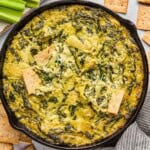 dairy free spinach artichoke dip in a skillet with crackers.