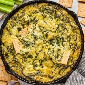 dairy free spinach artichoke dip in a skillet with crackers.