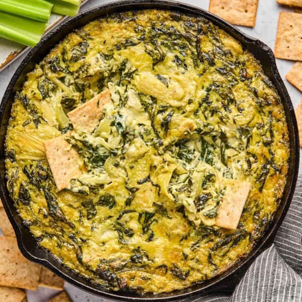 dairy free spinach artichoke dip in a skillet with crackers.