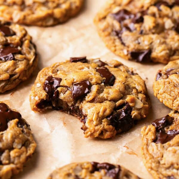 flourless oatmeal peanut butter cookie on parchment paper with a bite taken out.