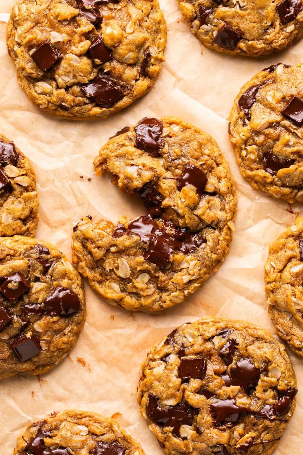 flourless oatmeal cookies on parchment paper with one broken in half.