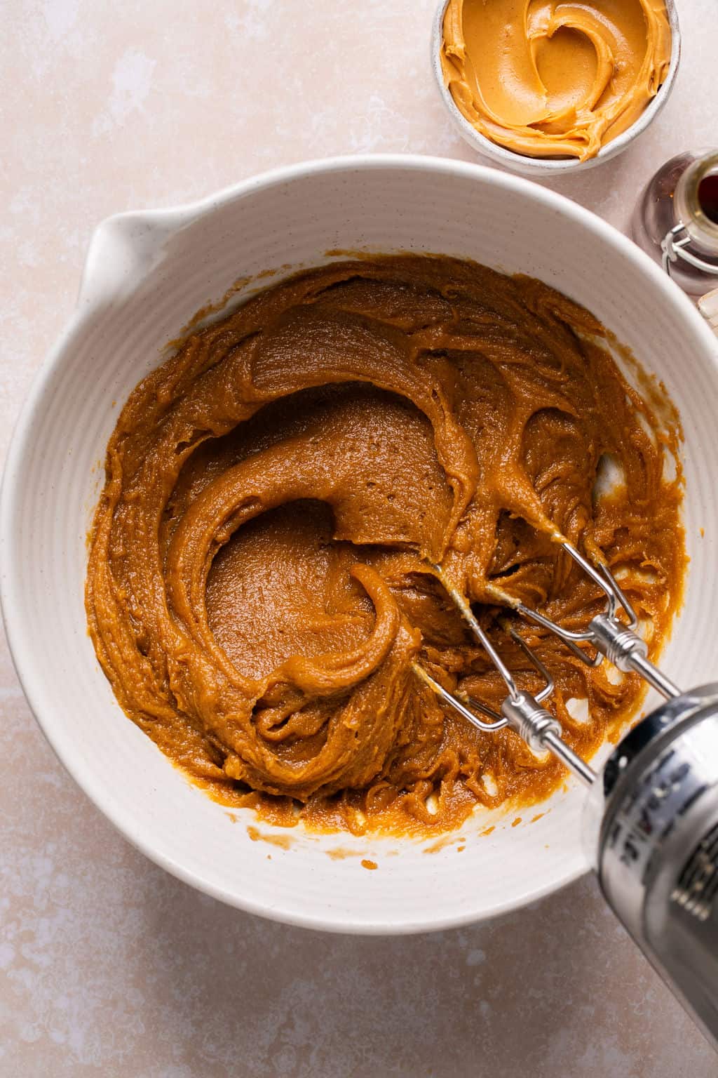 peanut butter, eggs, vanilla, and brown sugar mixed in a bowl with an electric mixer.