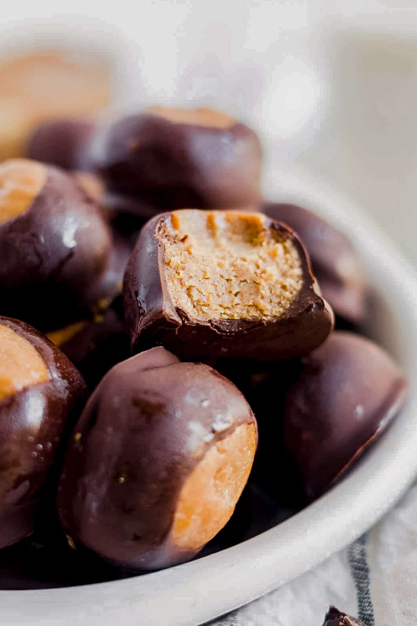 a pile of buckeyes with a bite taken out of one to see the healthier fudge center