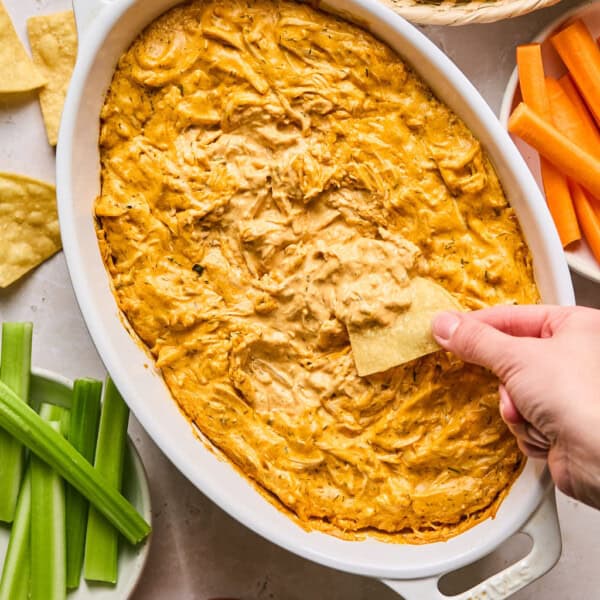 dairy free buffalo chicken dip in a dish with celery, carrots, and chips on the side.