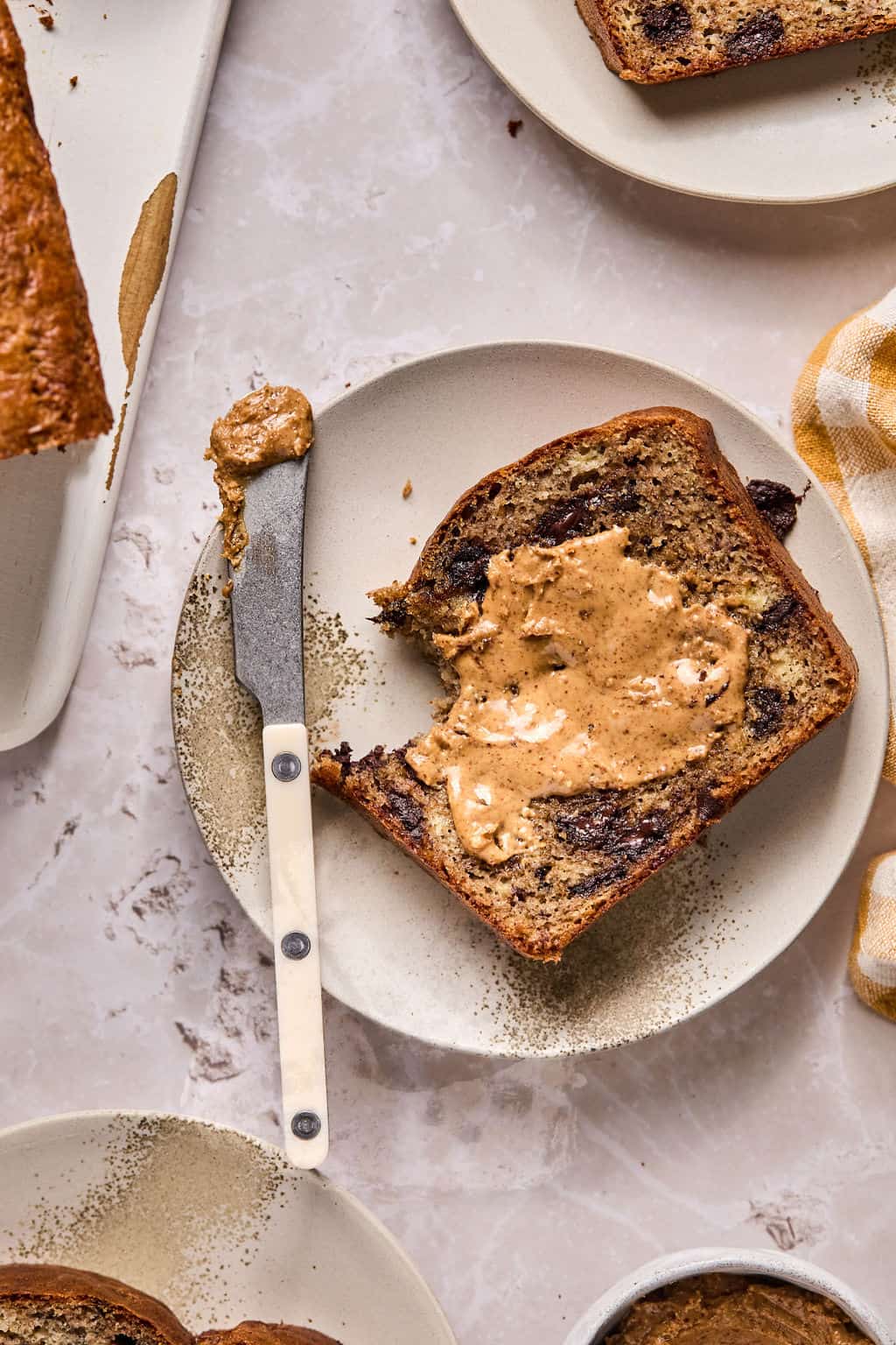 a slice of paleo banana bread on a plate with almond butter and a bite taken out.