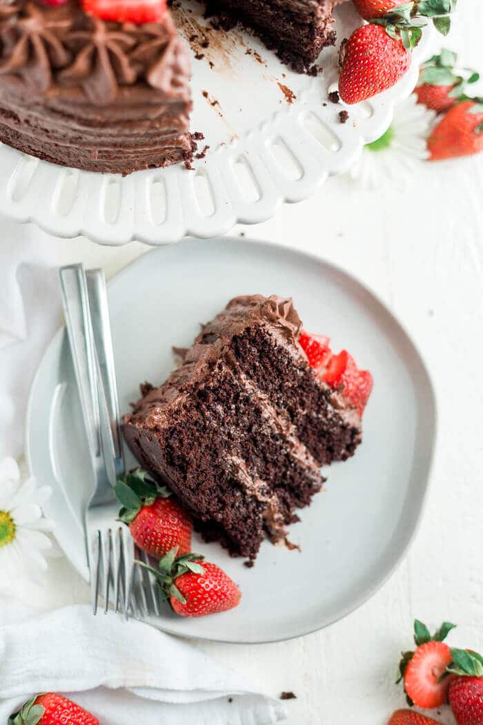 paleo chocolate cake recipe on a white plate with strawberries and two forks