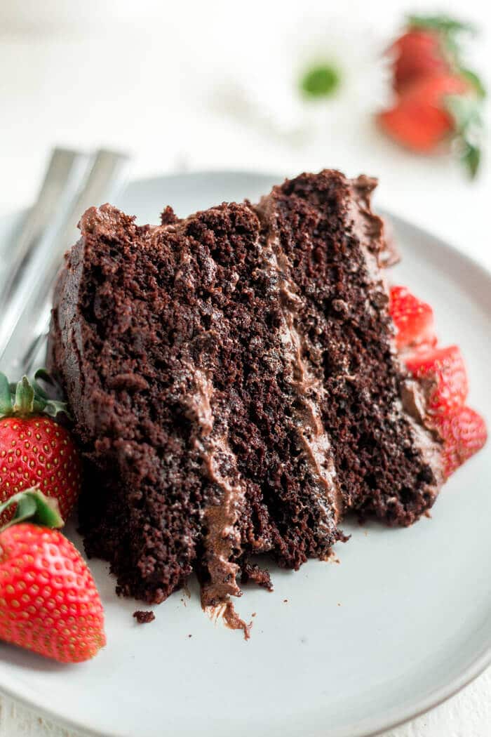 a piece of paleo chocolate cake on a plate with strawberries