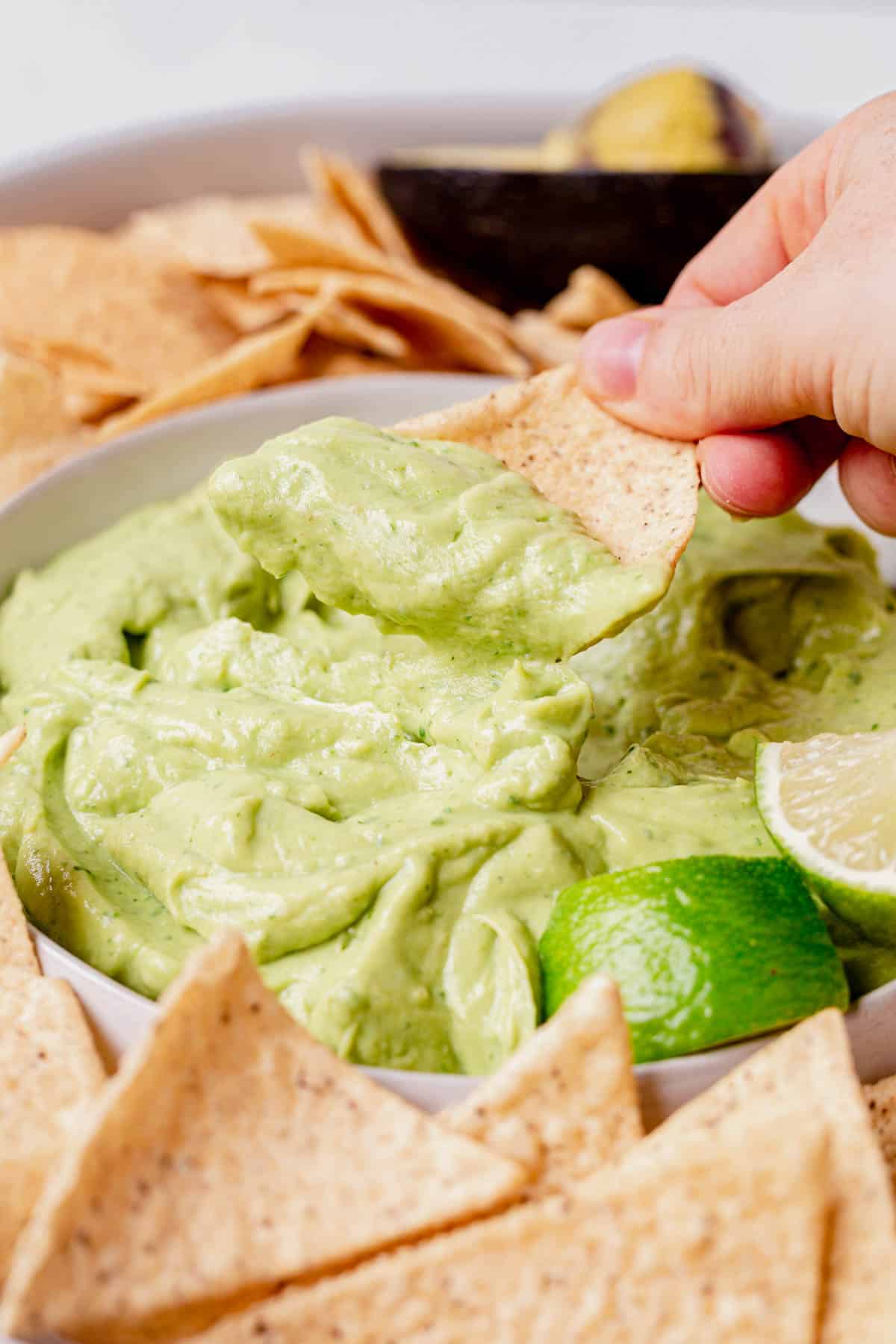 scooping avocado dip with a chip