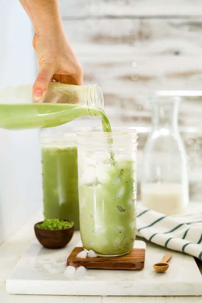 iced matcha latte being poured into a tall glass