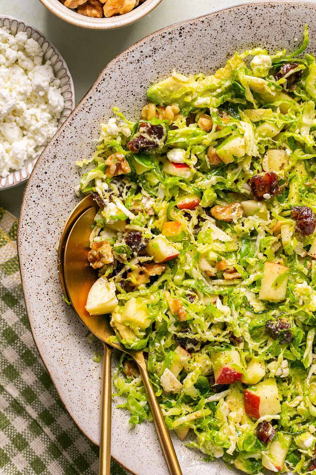 serving spoons in a serving bowl with shaved brussels sprout salad