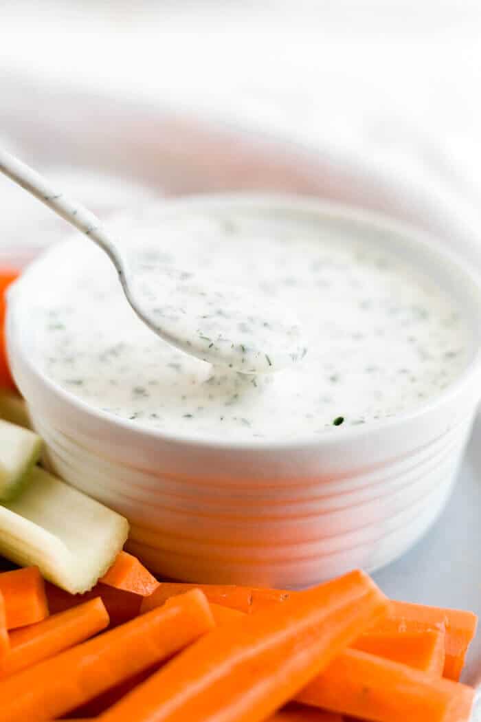 whole30 ranch dressing in a white bowl with a spoon scooping some out
