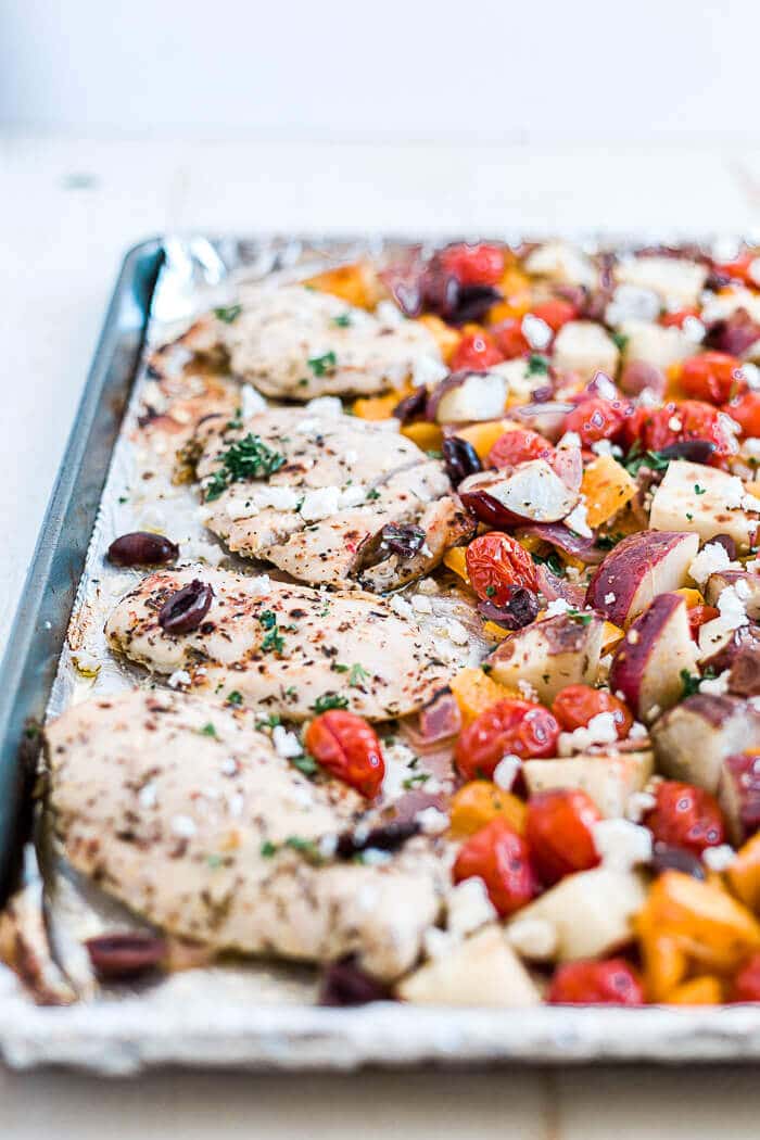baked greek chicken recipe with kalamata olives, feta cheese and veggies on a sheet pan