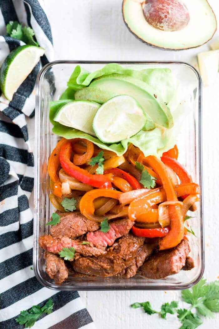 steak fajitas in a glass meal prep container with a side of avocado