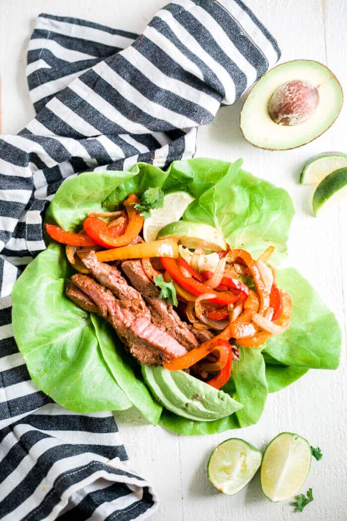 steak fajitas in a lettuce wrap with a lime wedge and half an avocado