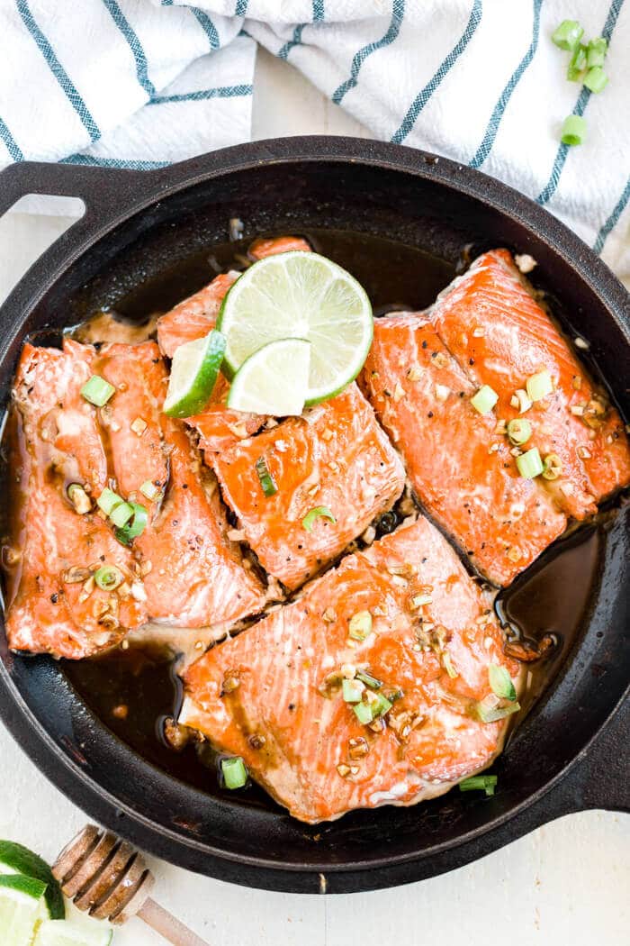 4 wild caught salmon filets with honey glaze in a skillet with lime and green onion