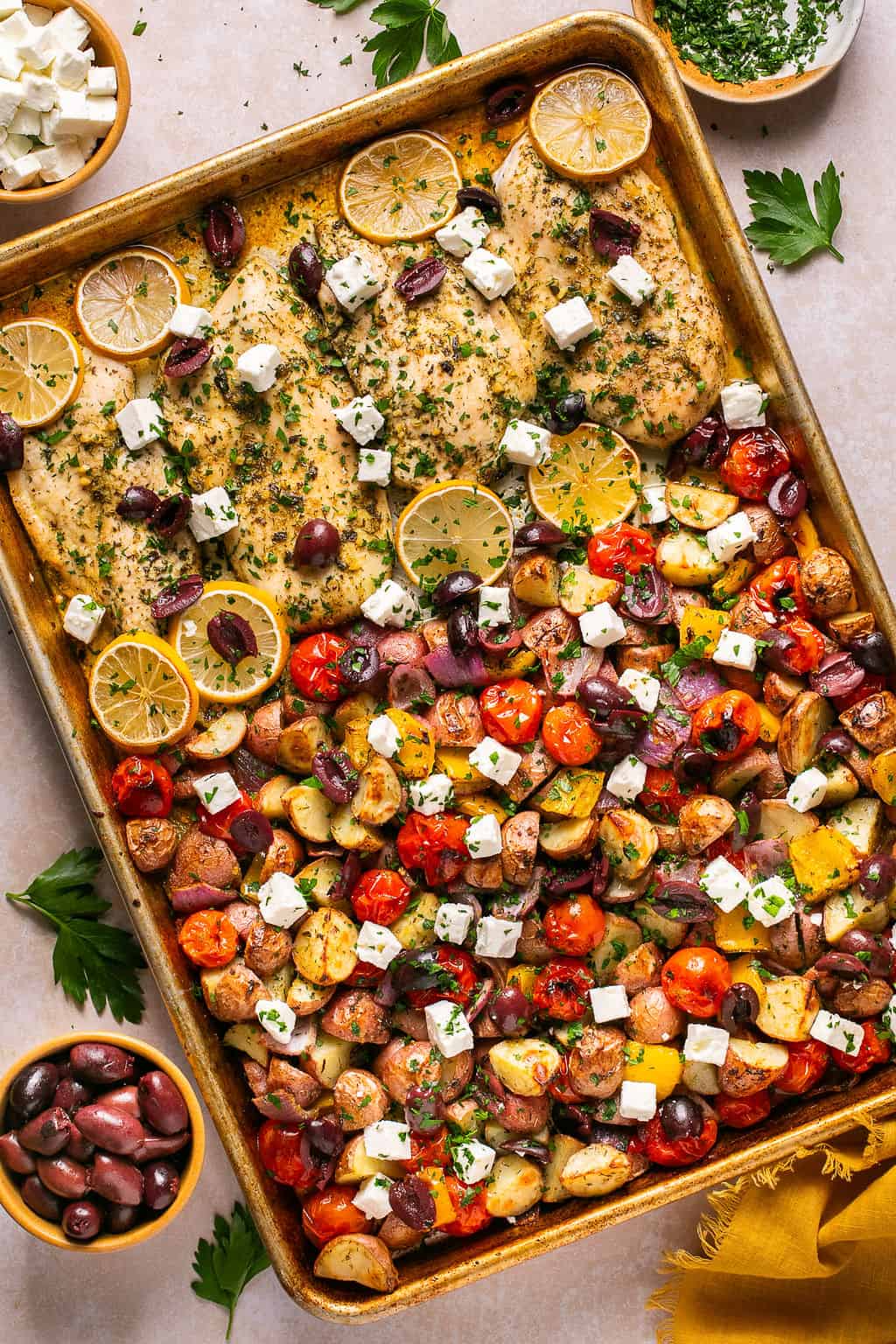 sheet pan greek chicken and vegetables with feta and parsley on top