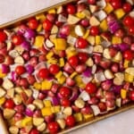 Greek vegetables coated in seasoning on a sheet pan
