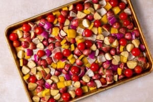 Greek vegetables coated in seasoning on a sheet pan