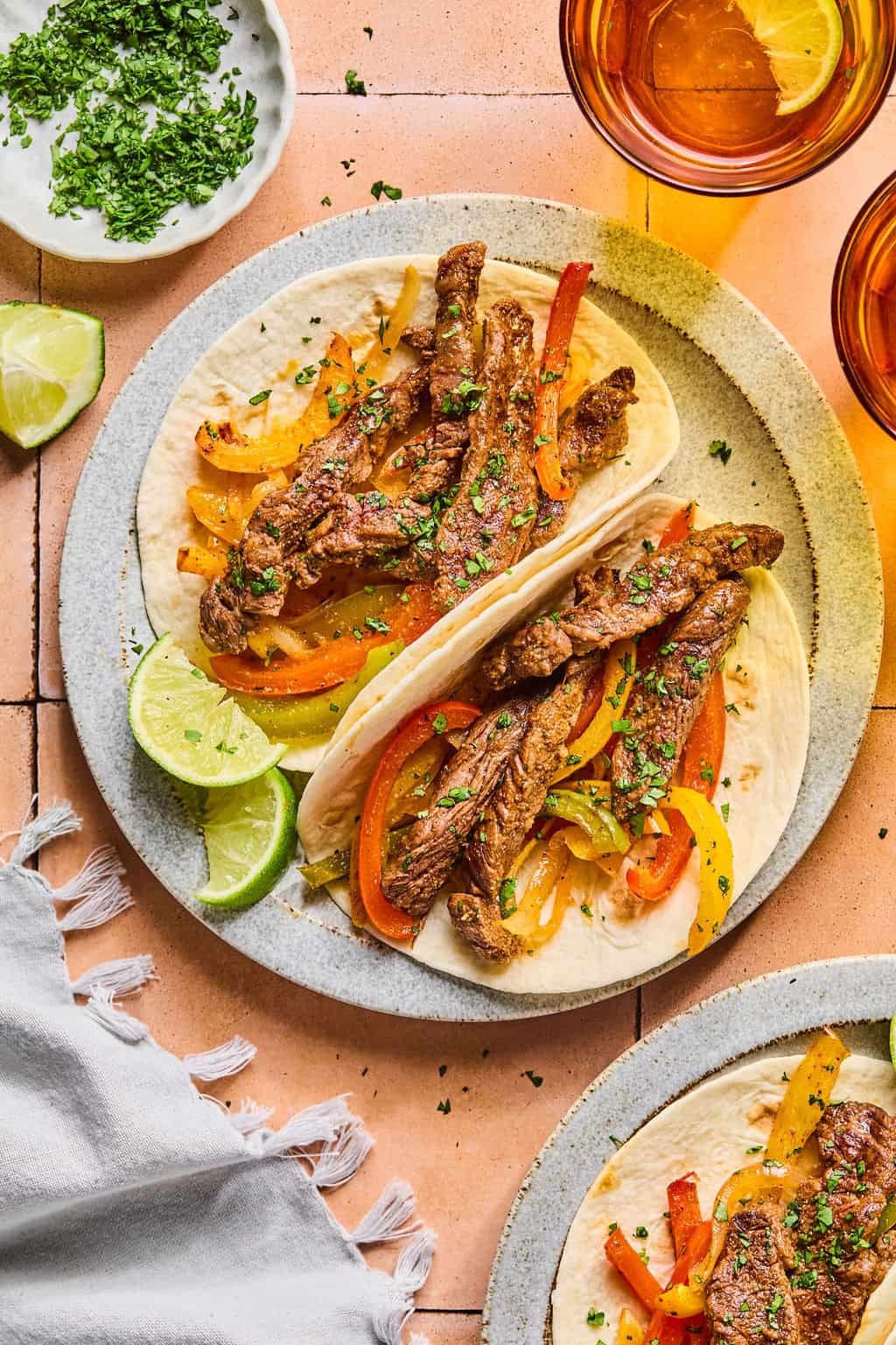two sheet pan steak fijtas on a plate with a lime wedge.