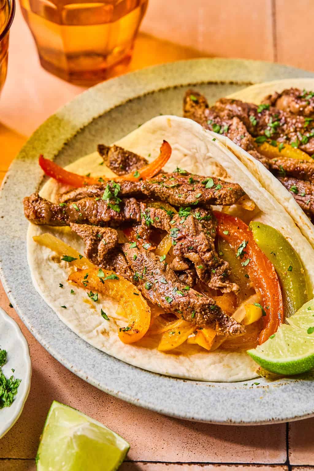 a steak fajita on a plate with cilantro and lime.