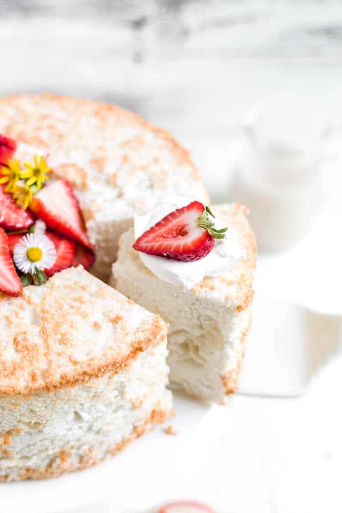 overhead view of a slices of gluten free angel food cake recipe being removed from the cake with a strawberry on top