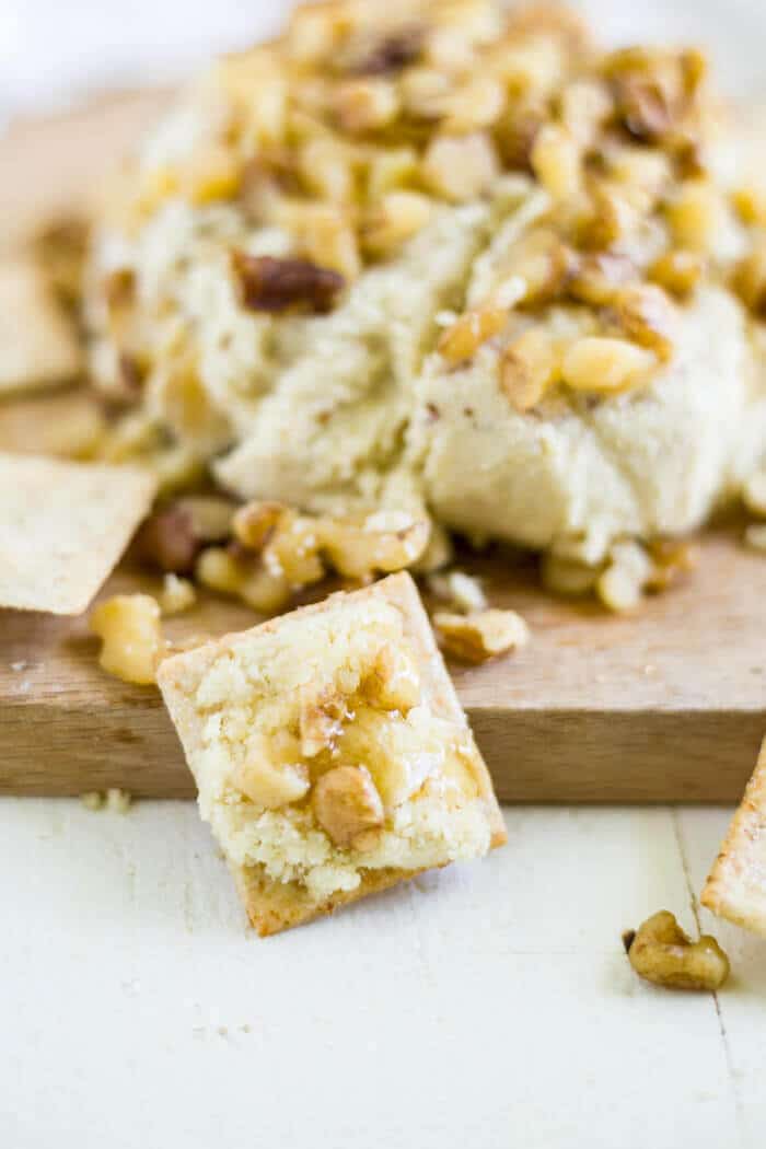 honey walnut vegan cheese spread recipe on a cracker with walnut and honey drizzle on top
