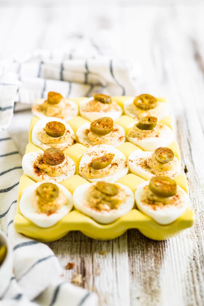 deviled eggs with bacon and jalapeno on a yellow tray