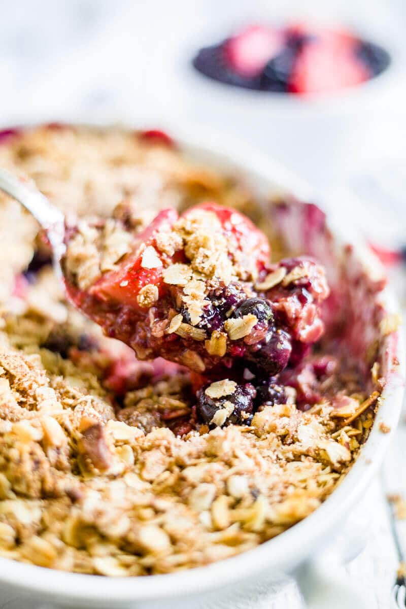 spoon scooping out gluten free berry crisp recipe from a baking dish