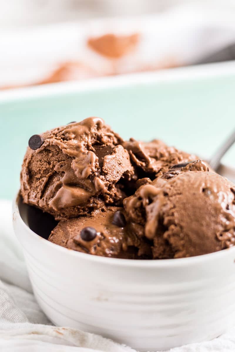 three scoops of chocolate banana ice cream in a white bowl with a spoon