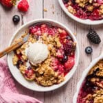 a bowl of gluten free berry crisp with a scoop of vanilla ice cream.