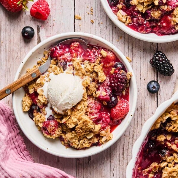 a bowl of gluten free berry crisp with a scoop of vanilla ice cream.