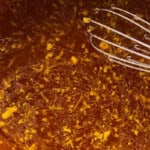 whisking a sticky orange sauce in a saucepan for crispy cauliflower.