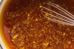 whisking a sticky orange sauce in a saucepan for crispy cauliflower.