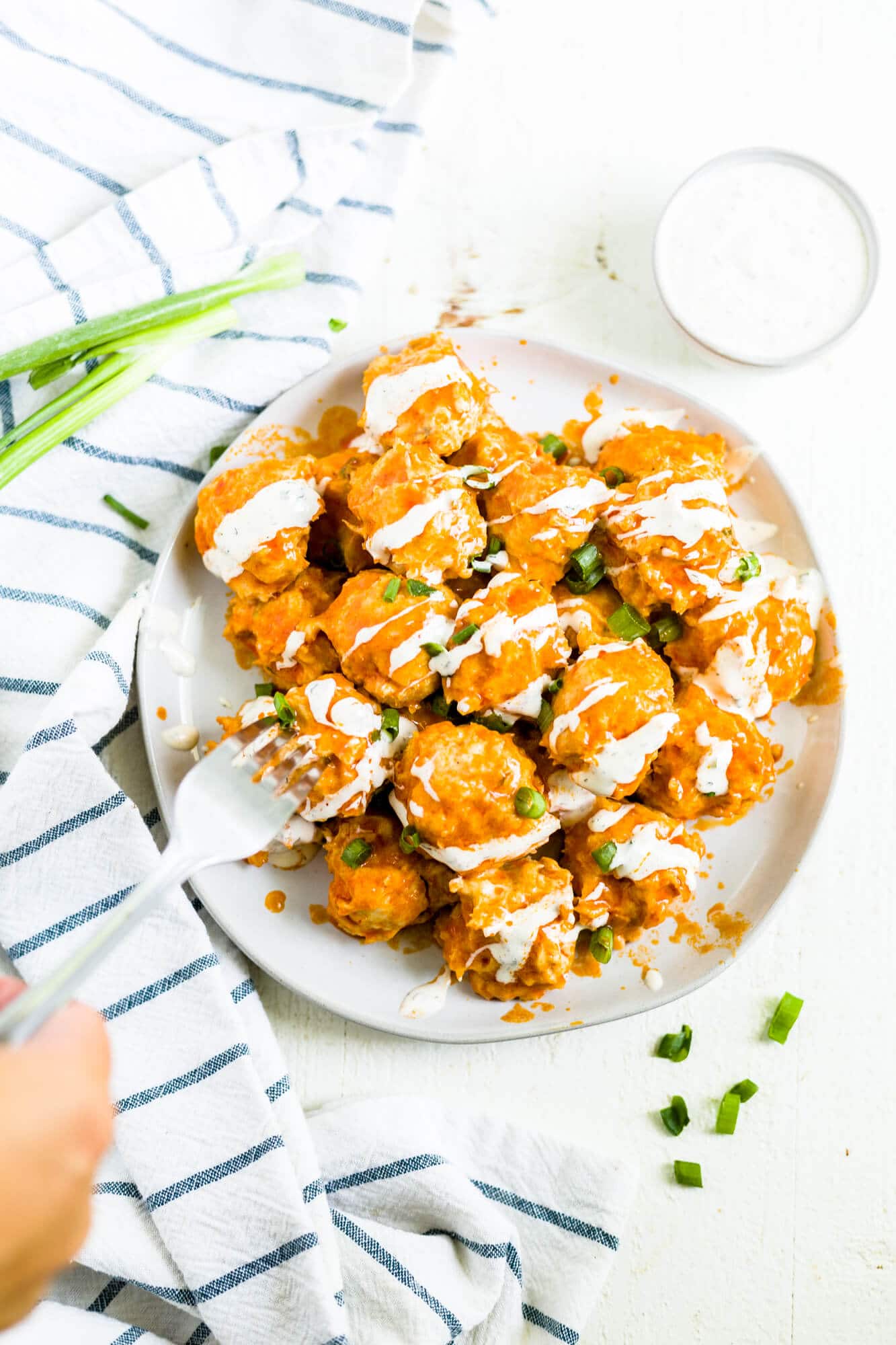 a plate of buffalo chicken meatballs drizzle with ranch dressing