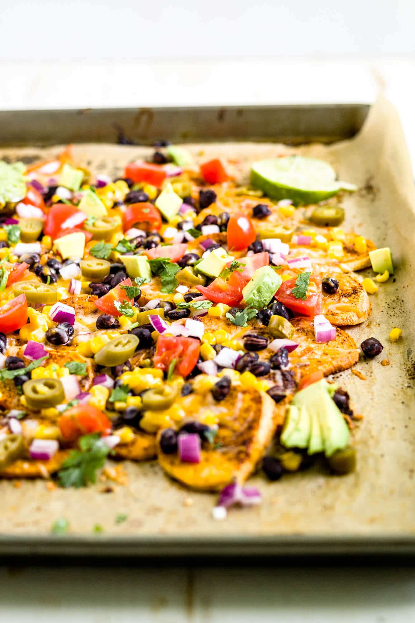 loaded sweet potato nachos on a baking sheet with parchment paper