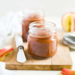 crock pot apple butter in a small glass mason jar with a spreading knife next to it