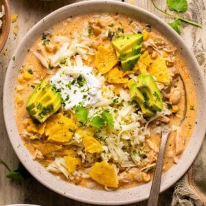 a bowl of healthy white chicken chili with tortilla chips and avocado.