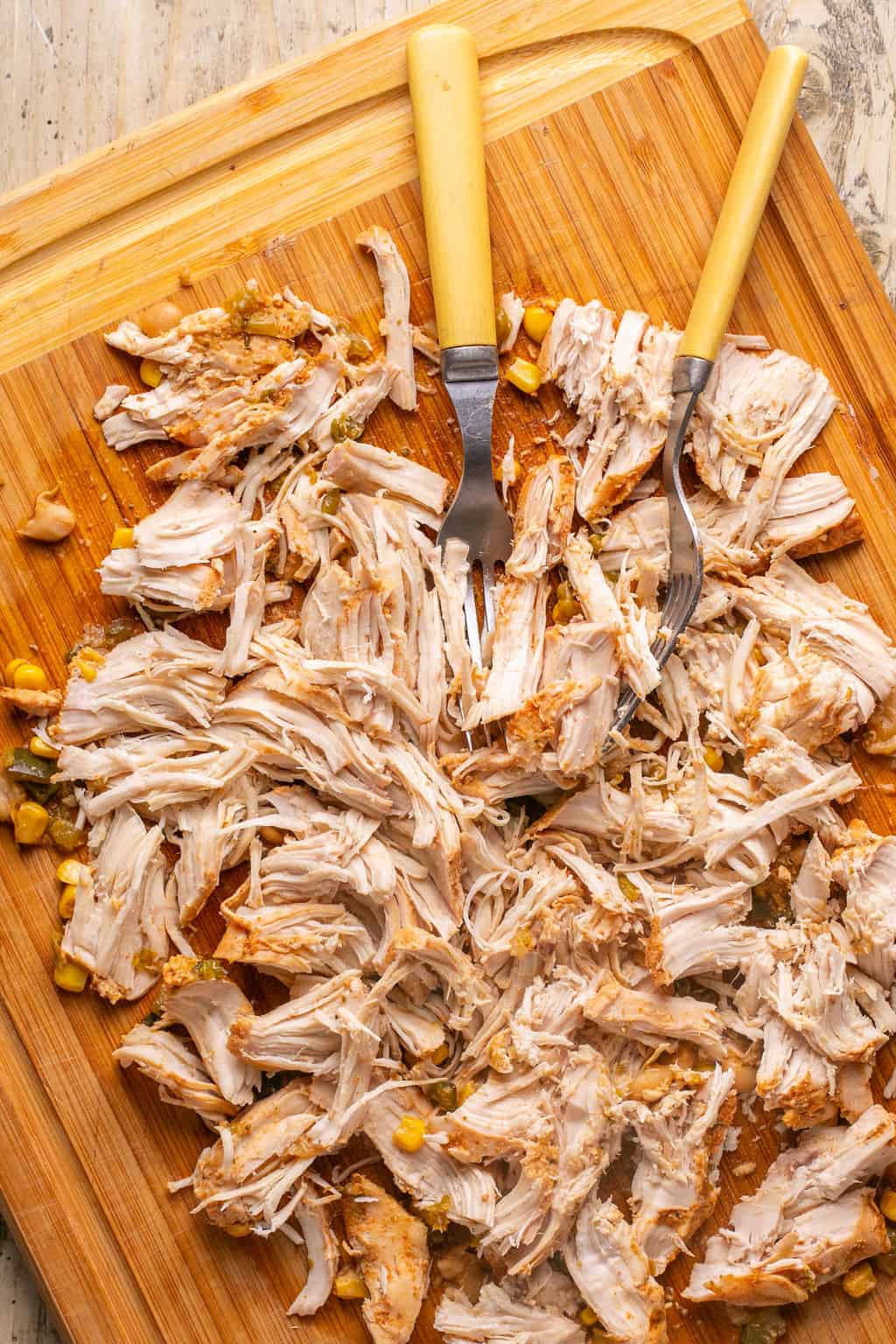 shredded chicken on a cutting board with two forks.