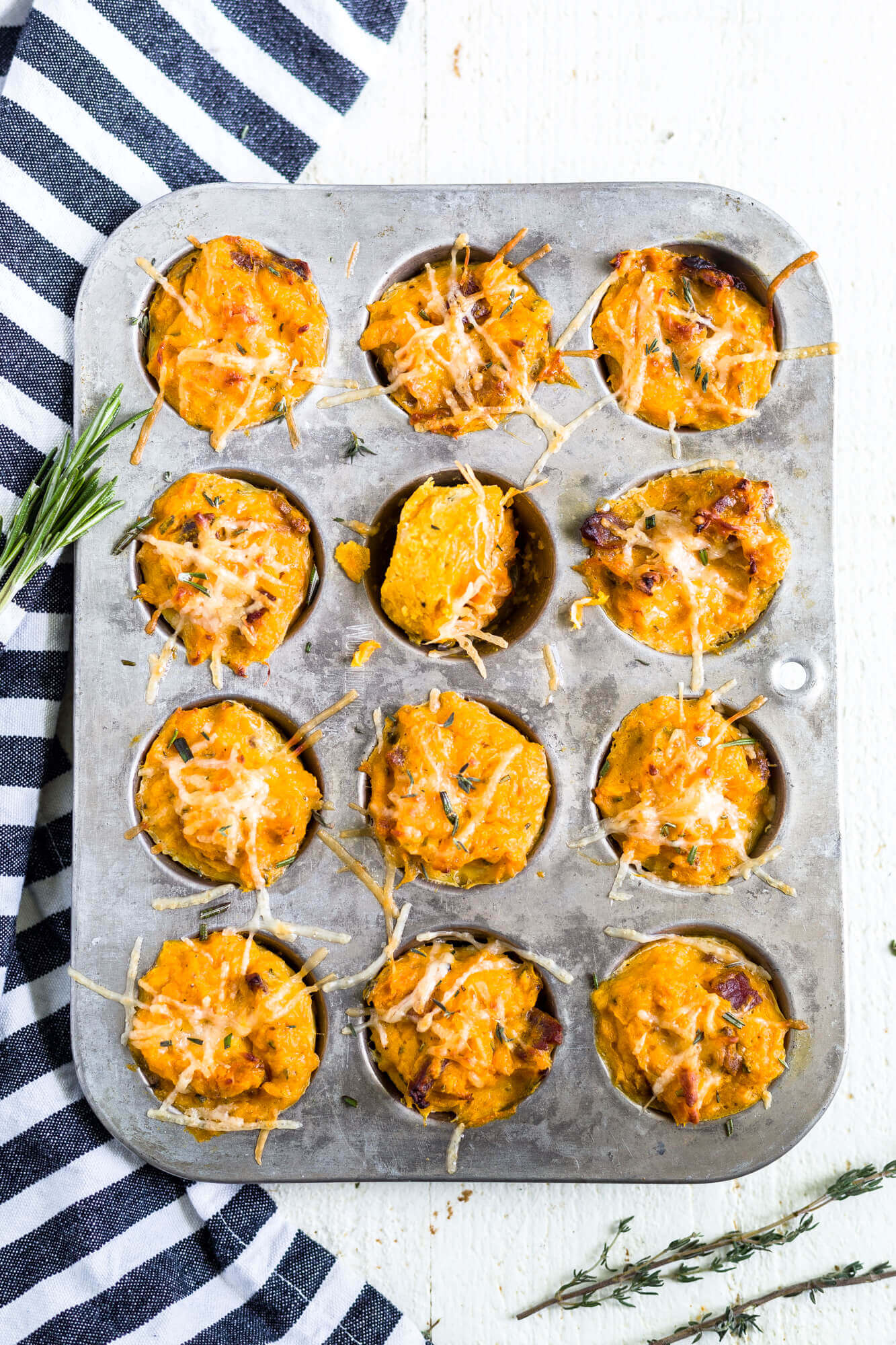 sweet potato puffs in a muffin tin with fresh herbs on top