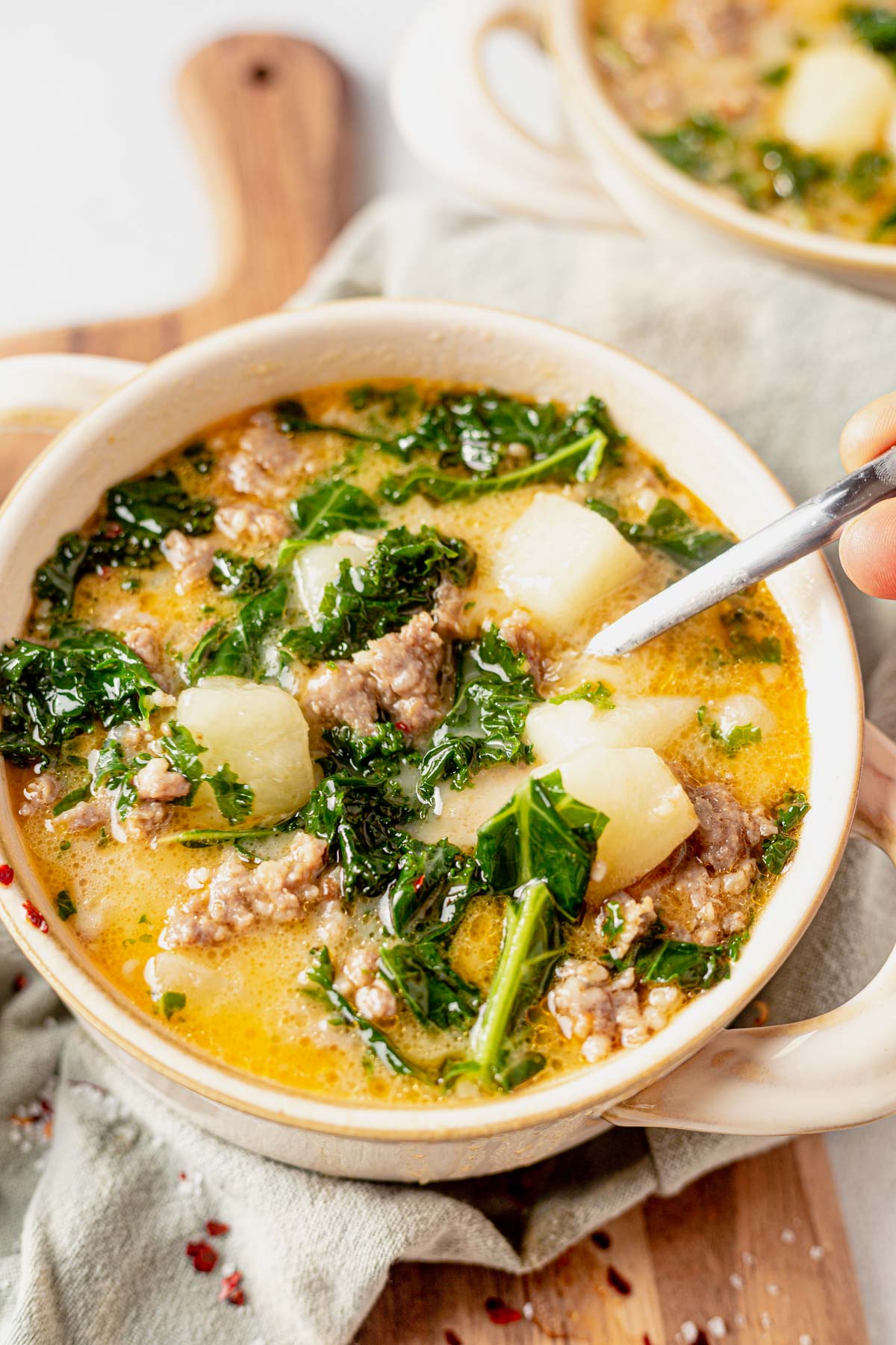 a soup bowl full of easy whole30 instant pot zuppa toscana with a spoon