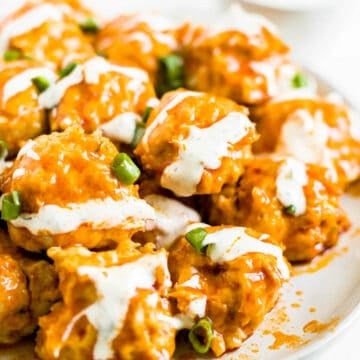 a plate of buffalo chicken meatballs with ranch dressing drizzled on top