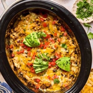 mexican casserole in a crock pot with melted cheese and taco toppings.